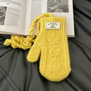 Détail de la moufle en laine mélangée jaune avec étiquette tissée et cordon tour de cou