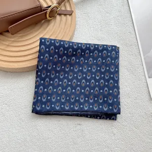 Detail of navy blue square scarf with geometric pattern on wooden board with leather strap