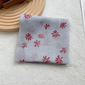Light blue semi-transparent cotton linen floral scarf on a wooden display stand
