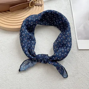 Detail of navy blue geometric pattern silk scarf styled as an elegant necktie accessory