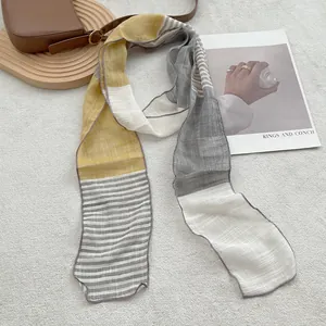 Detail of pure linen scarf with striped texture and color block design on wooden tray