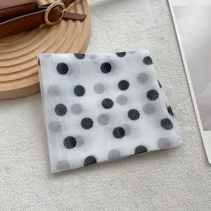 Foulard en mesh à pois sur fond pelucheux avec un présentoir en bois minimaliste