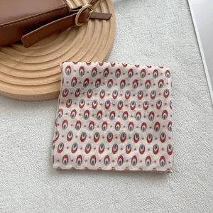 Detail view of cotton scarf with geometric eye patterns on white felt backdrop