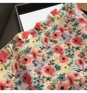 Detailed view of floral silk scarf fabric with tassels on a premium gift box base