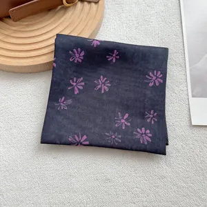 Close-up of cotton linen square scarf with purple daisy prints on dark fabric