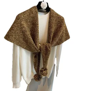 Thick wool knit triangle shawl with decorative pom-poms in warm mustard yellow blend