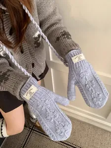 Détail de mitaines bleu clair en tricot torsadé avec texture laine et cordon de cou