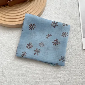 Detail of a light blue cotton linen square scarf with delicate brown floral star patterns