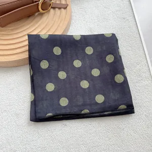 Détail d'un foulard carré bleu marine à pois vert olive avec une texture de vagues subtile