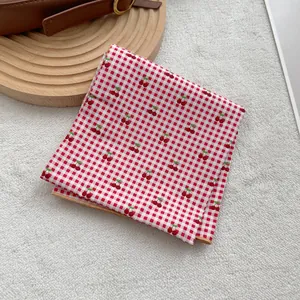 Detail of red and white checkered square scarf with cherry prints and yellow edges