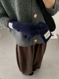 Detail of dark blue knit gloves with stylish white logo label for winter warmth