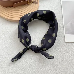 Vue détaillée d'un foulard en soie léger à pois noué sur un fond à texture douce