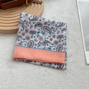 Dettaglio foulard in cotone e lino con motivi paisley e bordi color corallo