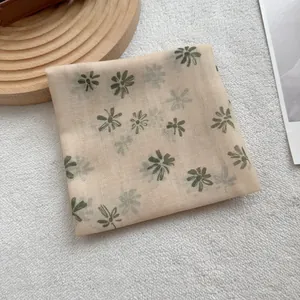 Detail view of semi-transparent beige mesh scarf featuring vintage green daisy floral pattern