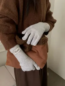 Detail of light gray knit gloves with decorative wrist label and thick thermal texture