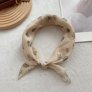 Detail of a beige linen neck scarf with retro green daisy pattern and fine edge stitching
