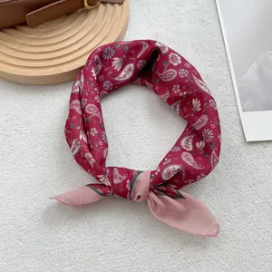 Dettaglio di un foulard bordeaux con motivo paisley annodato su pelliccia bianca