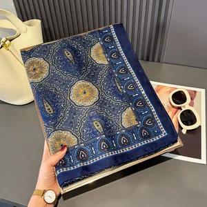 Detailed shot of dark blue floral silk scarf with paisley pattern on a gold gift box