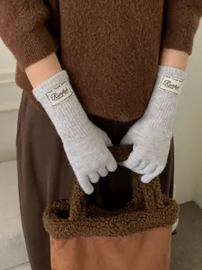 Detail of light grey ribbed knit gloves featuring a minimalist white fabric brand label