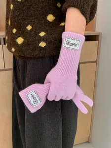 Detailed knit texture of pink long gloves with white woven label in a cozy indoor setting