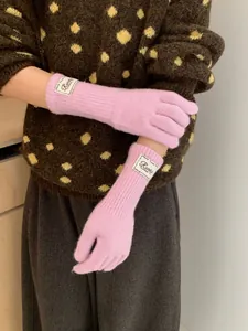 Close-up of pink knit gloves with vertical ribbed texture and decorative cloth label