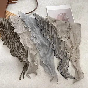 Detail of linen triangle scarves with delicate ruffle edges and retro floral patterns