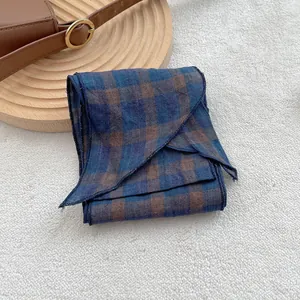 Detail of blue and brown checkered linen scarf on soft white fabric background