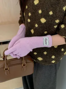 Detail of pink fine knit gloves with ribbed cuffs and branded label for winter
