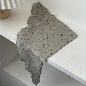 Detail view of floral cotton scarf with wave-stitched edges and vintage print