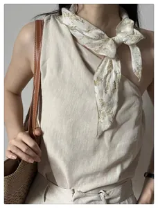 Detail of floral vintage headscarf paired with beige linen top and woven tote bag