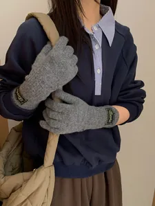 Detail view of light gray knitted gloves featuring retro woven labels and warm textures
