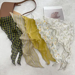Detail of four linen triangle scarves with plaid and floral patterns and wavy edges