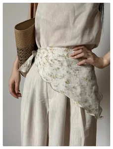 Detail of floral silk scarf tied as a belt on beige linen trousers for a retro french look