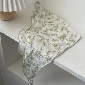 Macro detail of cream floral triangle scarf with scalloped gray edges and thin fabric texture