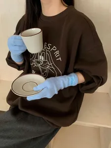 Close-up of blue knitted gloves with ribbed cuffs paired with a brown cotton sweatshirt