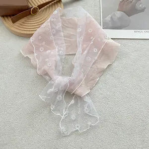 Detail van roze chiffon sjaal met wit kant en geborduurd madeliefjespatroon erop