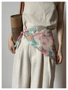 Close-up of floral print scarf tied as waist accessory over beige linen pants set