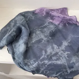 Detail of smoky gray and purple tie-dye pleated cotton linen scarf with fine texture