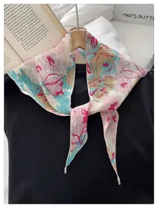 Detail of floral print scarf on wooden hanger with vintage book and soft lighting