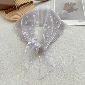 Detail van een elegante semi-transparante sjaal met witte madeliefjes op grijze stof