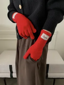 Detail of red knit gloves with white logo label and ribbed cuff for autumn warmth