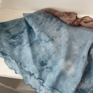 Detail of gradient blue and brown linen scarf featuring artistic tie-dye and wavy edges