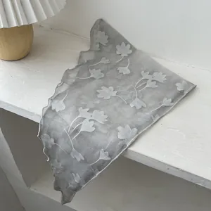Detail van een grijze transparante sjaal met geschulpte randen en witte bloemenpatronen