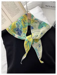Close-up of floral scarf texture showing delicate yellow fabric and vintage flower pattern