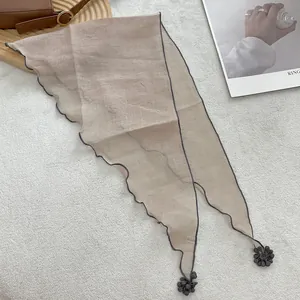Detail of champagne lace triangle scarf showing wavy edges and 3D floral ball pendants