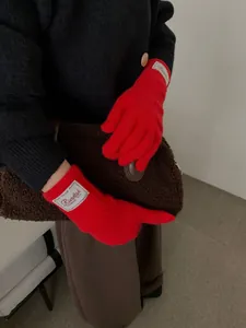 Detailed view of red knitted gloves with ribbed cuffs and fashion woven label for women