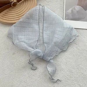 Detail of light blue pleated linen headscarf with scalloped edges on neutral carpet