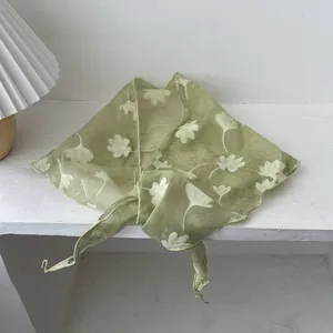 Detail van lichtgroene bloemen sjaal met witte ginkgo bladeren op zachte gaas stof