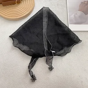 Detailed view of lightweight black lace triangle scarf with elegant pom-pom pendant