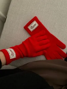 Detailed close-up of red knit long gloves with vintage white label and ribbed cuffs